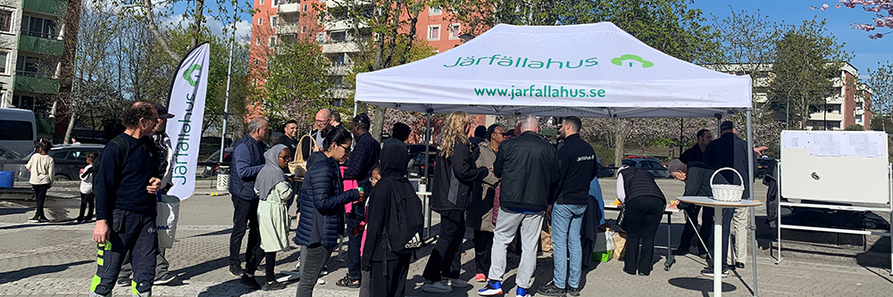 Tält med Järfällahus logo samt människor som samlats.